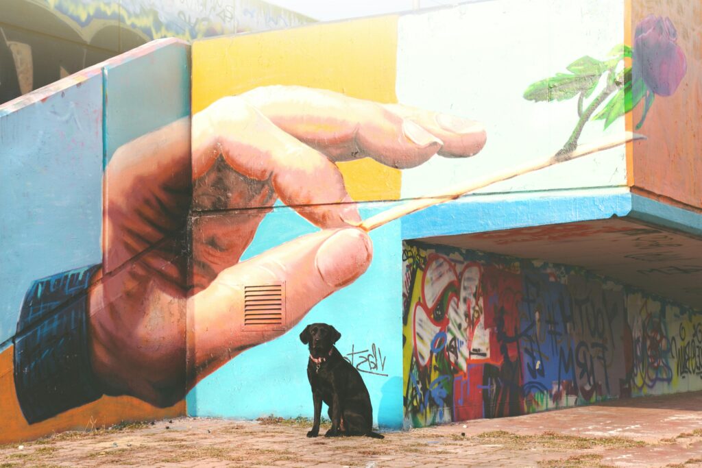 Colorful mural depicting a hand and rose with a black labrador sitting below in Prague.